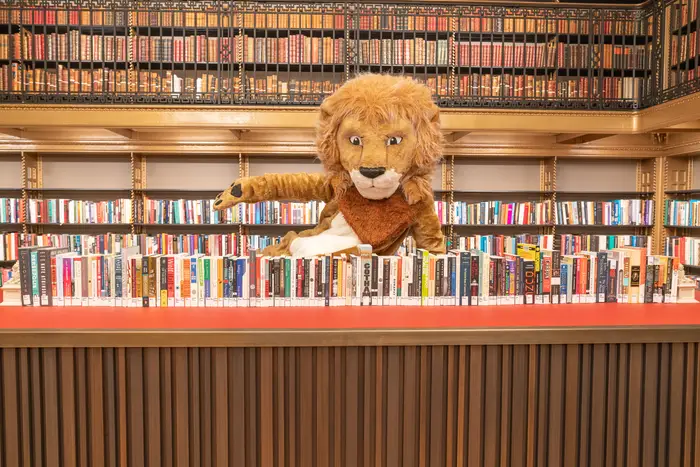 A lion mascot with books in the NYPL